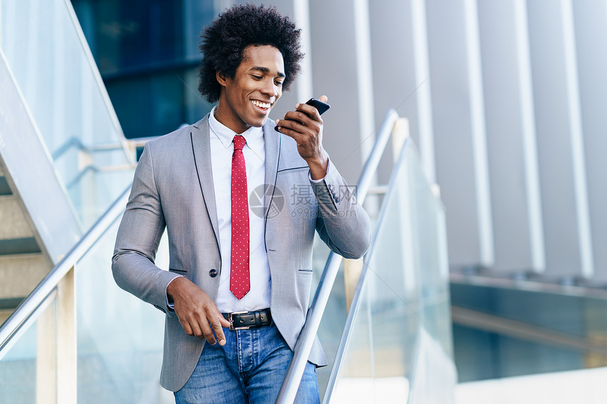 黑人商人办公楼附近用智能手机发送语音留言有AFRO头发的男人黑人商人办公楼附近用智能手机图片