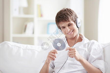 CD格式个带着耳机音乐CD的年轻人手中背景