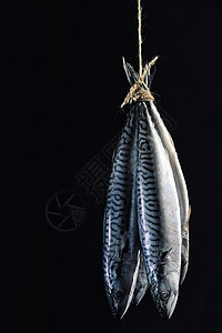 烟熏鲭鱼黑色背景上隔离的绳子上潮湿的高清图片素材