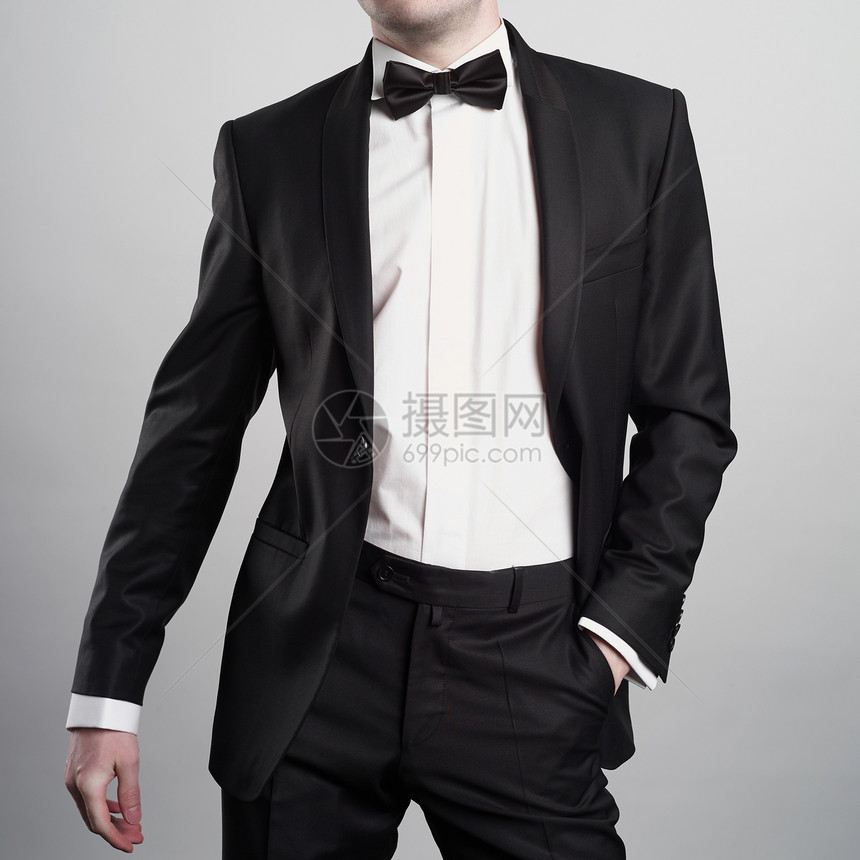 时尚男人的照片,穿着优雅的黑色西装领带时尚的年轻模特姿势摄影工作室奢华的夜晚吸烟与白色衬衫图片