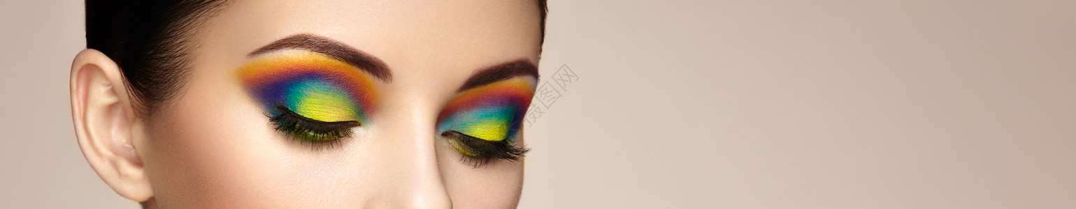 女性眼睛用彩虹化妆长长的睫毛,生动的五颜六色的眼影美丽,背景图片