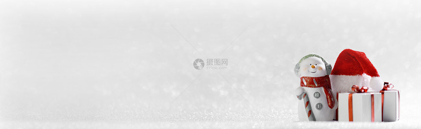 圣诞快乐新年贺卡快乐的雪人站圣诞礼物圣诞老人的帽子上银色的闪光背景带圣诞礼物的雪人图片