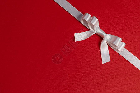 红纸背景上的白色缎带蝴蝶结红色的白色蝴蝶结图片