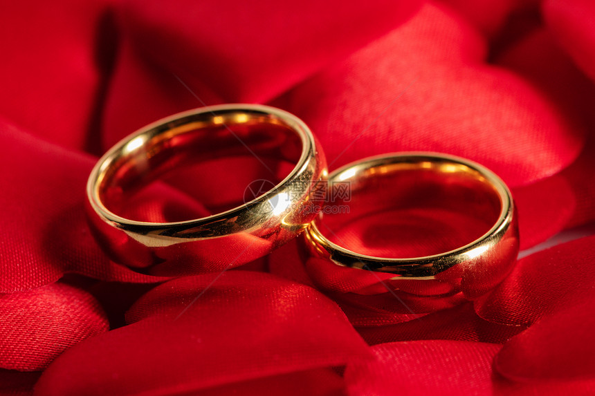红色缎心背景上的两个金色结婚戒指红色的金色结婚戒指图片