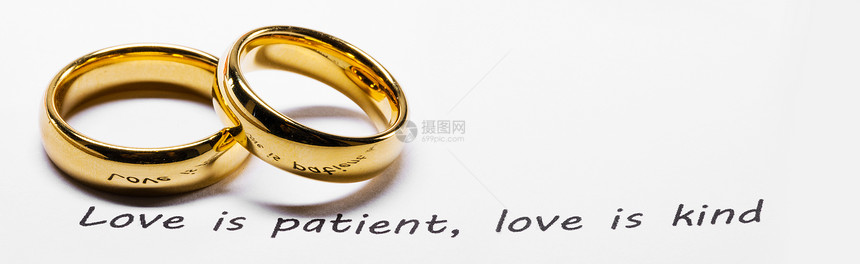 两个金色的结婚戒指圣经书上的短语特写,爱耐心的,爱善良的圣经短语上的金色结婚戒指图片