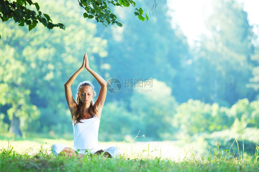 瑜伽女人穿着白色的绿色公园草地上的莲花阿莎娜姿势公园里的瑜伽女人图片