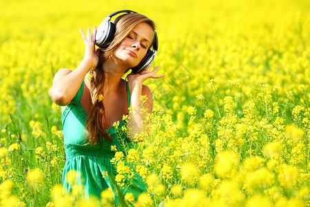 带着耳机油籽花田听音乐的年轻女人听音乐图片