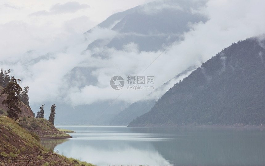 平静的景色加大的山湖旁边,岩石平静的水中反射图片