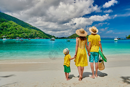 海滩上的家人,穿着黄色衣服的年轻夫妇三岁的男孩塞舌尔的暑假马海港短裤高清图片素材