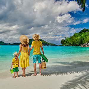 海滩上的家人,穿着黄色衣服的年轻夫妇三岁的男孩塞舌尔的暑假马海港站高清图片素材