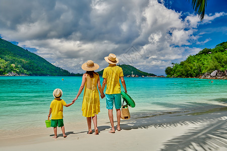 海滩上的家人,穿着黄色衣服的年轻夫妇三岁的男孩塞舌尔的暑假马海港水高清图片素材