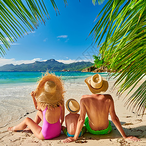 年轻的夫妇与小男孩在美丽的海滩背景图片