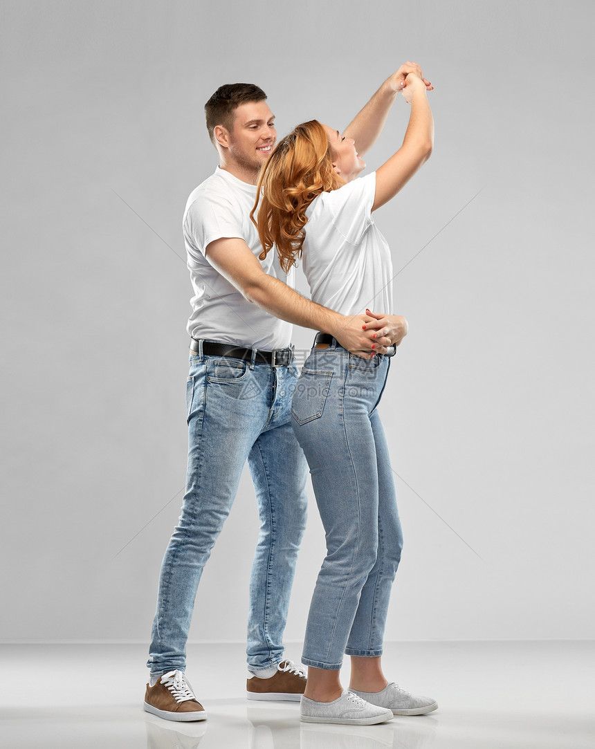关系人的幸福的夫妇白色T恤跳舞灰色背景的肖像穿着白色T恤跳舞的幸福夫妇的肖像图片