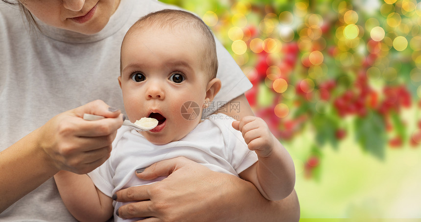 孩子,饮食食物的母亲与勺子喂养小婴儿夏季花园背景用勺子喂小宝宝来亲近妈妈图片