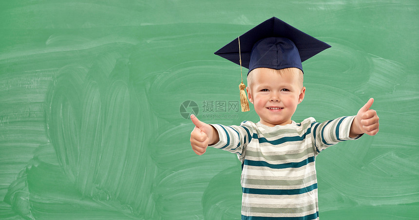 小学,学前教育儿童微笑的小男孩灰泥板上的肖像,绿色粉笔板背景上竖起大拇指快乐的小男孩迫击炮板上竖起大拇指图片
