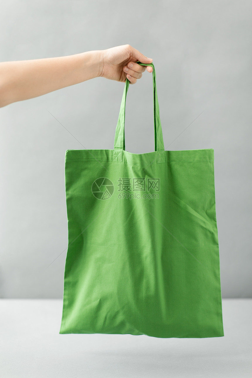 消费主义生态友好的手可重复用的帆布袋,用于灰色背景下的食品购物手持可重复用的帆布袋进行食品购物图片
