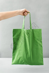 消费主义生态友好的手可重复用的帆布袋,用于灰色背景下的食品购物手持可重复用的帆布袋进行食品购物背景图片
