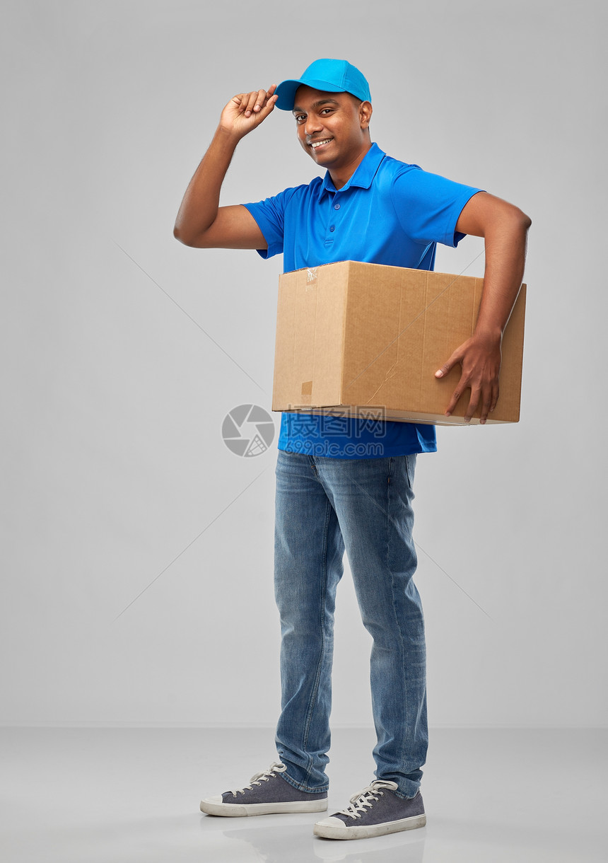 邮件服务装运快乐的印度送货人与包裹箱蓝色制服灰色背景快乐的印度送货人,包裹箱蓝色的图片