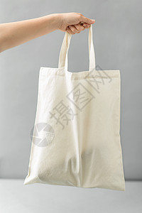 帆布袋素材消费主义生态友好的手可重复用的帆布袋,用于灰色背景下的食品购物手持可重复用的帆布袋进行食品购物背景