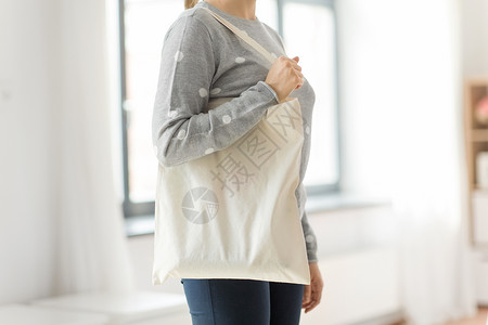 帆布袋素材消费主义生态友好的女与白色可重复用的帆布袋,用于灰色背景下的食品购物妇女与可重复用的帆布袋食品购物背景