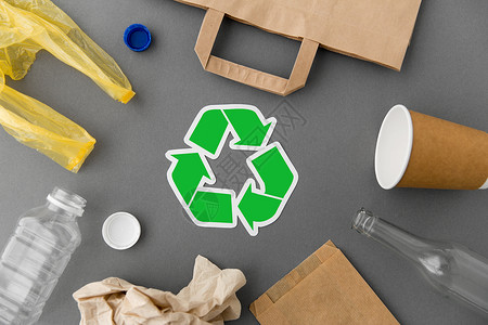 纸张浪费回收,垃圾处理生态绿色回收符号与家庭废物灰色背景绿色回收符号与家庭废物灰色背景