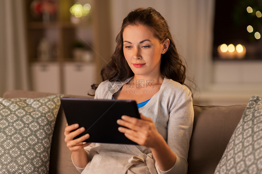 人,技术互联网快乐的女人坐沙发上与平板电脑电脑家里晚上晚上家用平板电脑的快乐女人图片