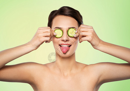 美丽,护肤排美丽的女人制作黄瓜眼罩,并她的舌头石灰绿色的自然背景美丽的女人用黄瓜做眼罩背景图片