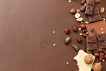 糖果,糖果食品牛奶,深色白色巧克力棒与榛子可可豆的棕色背景巧克力棒与榛子可可豆背景图片