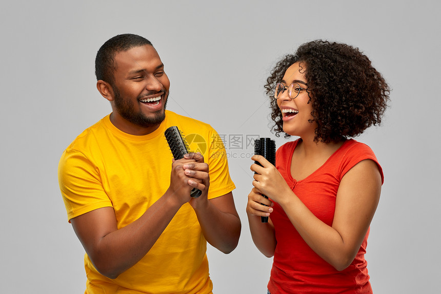 有趣人的快乐微笑的非裔美国夫妇灰色背景下唱歌给梳子快乐的非洲夫妇唱歌给梳子图片