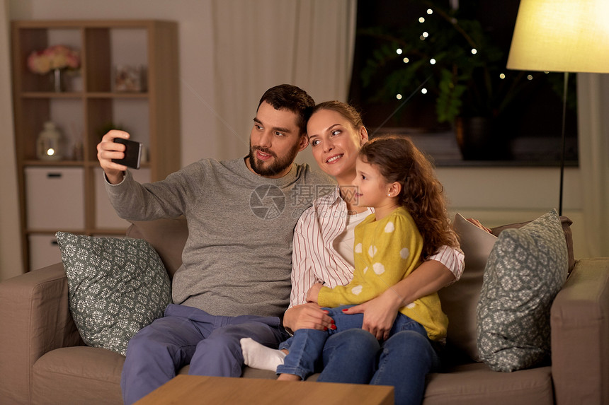人们,家庭技术快乐的父亲,母亲小女儿家里用智能手机自拍快乐的家人晚上家自拍图片
