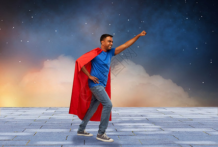 做自己的英雄超级力量人的印度男人穿着红色超级英雄斗篷,星空背景上做获胜的手势穿着超级英雄斗篷的印度男人做了获胜的手势背景