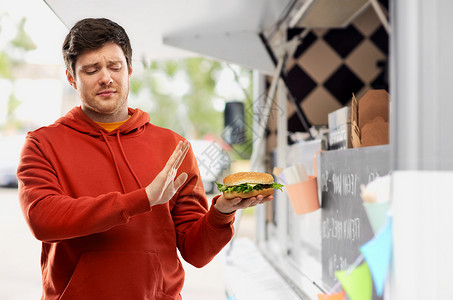 快餐,健康的饮食人们的年轻人穿着红色连帽衫,拒绝汉堡食品卡车街头背景年轻人拒品卡车上吃汉堡包背景图片