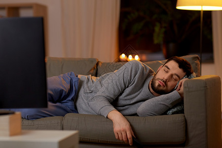 休闲人们的男人睡沙发上,晚上家看电视男人睡沙发上,家里有电视遥控器图片