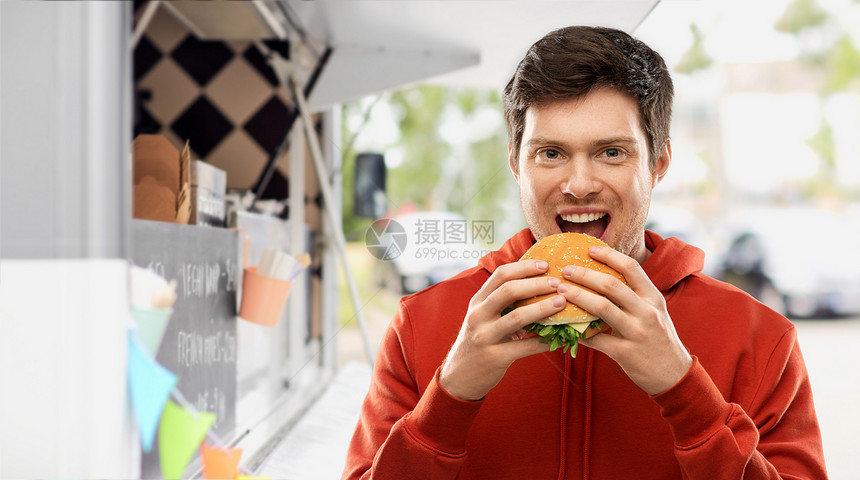 快餐,外卖人们的快乐的微笑年轻人穿着红色帽衫,街上的食品卡车上吃汉堡包快乐的年轻人食品卡车上吃汉堡包图片