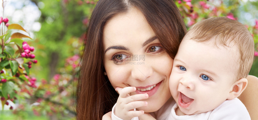 家庭母亲的快乐的微笑年轻母亲与小婴儿自然春天樱花背景母亲带着孩子春天的花园背景下图片