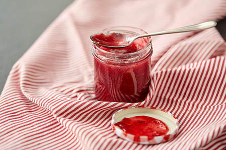 食物,蜜饯饮食梅森罐与红色覆盆子果酱勺子毛巾上梅森罐子,覆盆子果酱勺子毛巾上背景图片