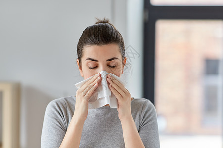 花粉热医疗保健,感冒,过敏人的生病的女人家里用纸巾吹鼻涕生病的女人家里用纸巾吹鼻子背景