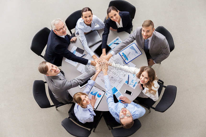 公司,人队合作的快乐的商业队坐桌子上堆叠的手快乐的商人堆砌双手图片