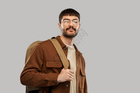 旅行,旅游人的年轻人戴着眼镜,背着灰色背景的背包戴眼镜带背包的年轻人图片