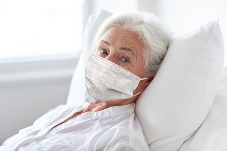 医学,健康安全大流行老年妇女病人躺床上,戴着面部防护医疗面罩,以防止医院病房的病疾病老妇病人戴着面具躺医院的床帮助高清图片素材