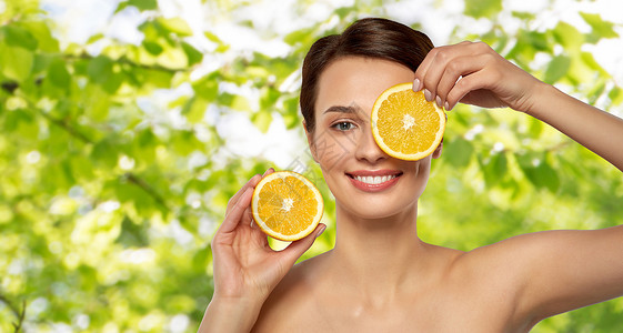 瞬间逆龄美容,护肤排美丽的女人制作橙色切片的眼罩绿色的自然背景美丽的女人用橘子片做眼罩背景