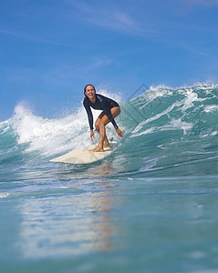 阳光明媚的日子里,女冲浪者蓝色的波浪上冲浪背景图片