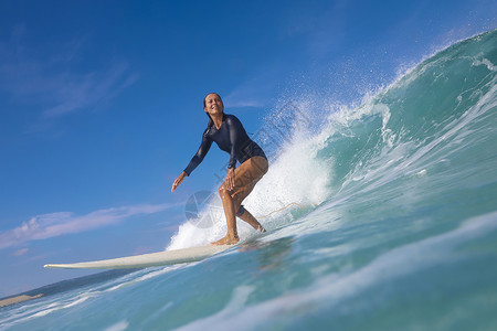 阳光明媚的日子里,女冲浪者蓝色的波浪上冲浪背景图片