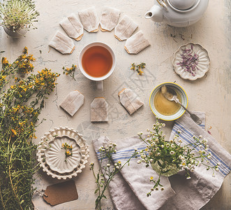 草药茶的健康的热饮各种新鲜的草药与杯凉茶,蜂蜜茶袋乡村的桌子背景上面的风景背景图片