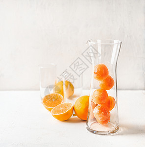 水果冰块橙汁水壶玻璃杯中,用于白色桌子上的提神饮料夏季饮料准备图片