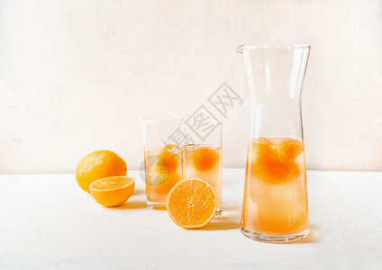 清爽的柠檬水与水果,冰块的橙汁水壶眼镜白色的桌子上图片
