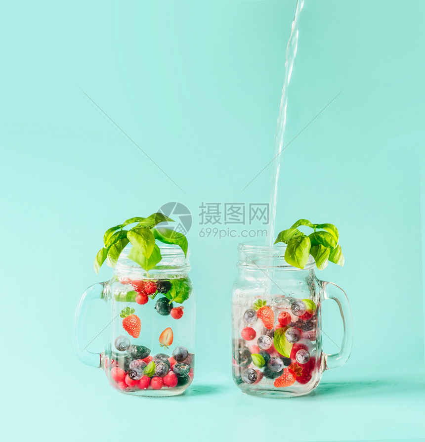 新鲜的水流进个瓶子里,里面有浆果解的水果,梅森罐里注入了水,阳光明媚的绿松石蓝色背景下,加入了叶子调味夏天的心情图片