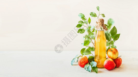 横幅与自制苹果醋玻璃瓶站白色桌子上,红色苹果绿叶白色的墙壁背景健康发酵食品保存苹果背景图片