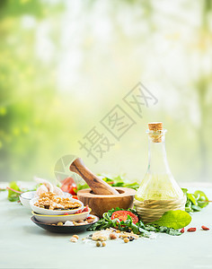 新鲜的沙拉配料站夏季自然背景的轻桌上橄榄油,坚果种子,沙拉叶,草药香料健康食品的夏季美食背景图片