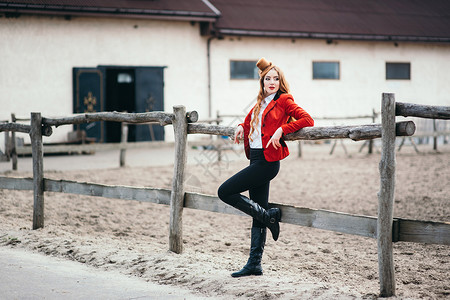 红发骑师女孩穿着红色开衫黑色高靴盯着篱笆图片